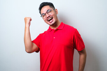 Young handsome man wearing casual shirt and glasses very happy and excited doing winner gesture with arms raised, smiling and screaming for success. Celebration concept