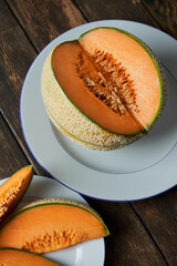 Wall Mural - Slices of Japanese melons, honey melon or cantaloupe on white plate. wooden table background. Best fruit in summer. Fruit. Healthy food concept. Flat-view