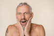 © InsideCreativeHouse - Shocked impressed caucasian mature middle-aged handsome man with bare shoulders shirtless with tattoo showing positive emotions isolated in beige background. Sale offer discount