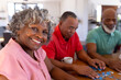 © WavebreakMediaMicro - Portrait of smiling multiracial senior woman solving jigsaw puzzle with male friends in nursing home