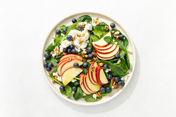 Wall Mural - Apple and spinach fresh sweet fruit salad with blueberry, cheese cottage and walnuts, top view