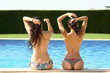 Girls in bikini sitting at pool.