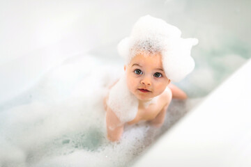 baby boy bathes in a bath with foam and soap bubbles