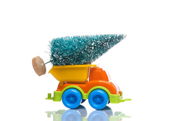 Wall Mural - Toy dump truck with christmas tree isolated on white background with reflection