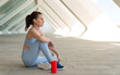 © Rob Wilkinson - Sporty, fit woman sitting relaxing with a bottle of water after exercise, urban background.