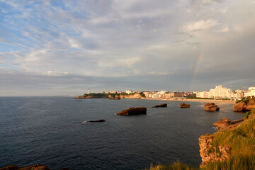 Wall Mural - Early summer in Biarritz, France. Beach, Surfing holidays. Lighthouse, clouds, Ocean, Biscay, Sunset, Rainbows