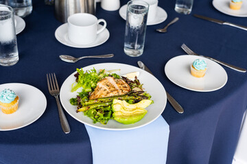 Chicken and avocado salad plated on fine dining table set with cupcake and blue color scheme 