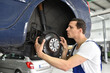 © industrieblick - car mechanic repairs brakes of a vehicle on the lifting platform in a workshop