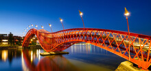 A Bridge In The City At Night. The Bridge Against The Sky During The Blue Hour. The Python Bridge, Amsterdam, The Netherlands. Panoramic Photography For Design And Background..