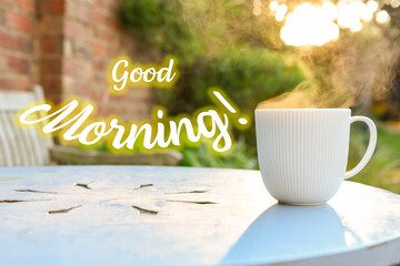 Good morning message at sunrise with hot drink on an outdoor garden table