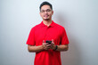 Portrait young Asian man in casual red shirt using smartphone trading or chatting