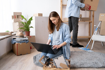 Wall Mural - Caucasian young woman with laptop planning design of new flat, freelancer moving and working on laptop