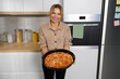 © Andrii  - Cheerful housewife with homemade pizza in her hands cooked for a family recipe