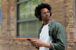 © JustLife - Handsome young man with headphones. Man listening the music while walking through the city.