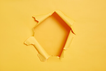 Big paper hole in center of yellow background, bank space to insert your advertising content, promotion or text information. Torn ripped wall. Breakthrough.