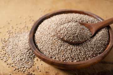 Wall Mural - White chia seeds and wooden spoon in a wooden dish placed on a wooden background.