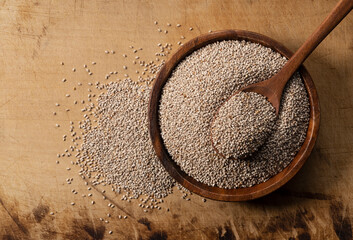 Wall Mural - White chia seeds and wooden spoon in a wooden dish placed on a wooden background.