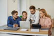 © Studio Romantic - Smiling teen students sit at desk working together on computer prepare for report at university. Happy young people brainstorm collaborate together on laptop in office. Teamwork concept.