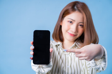 Image of young Asian girl using smartphone on blue background