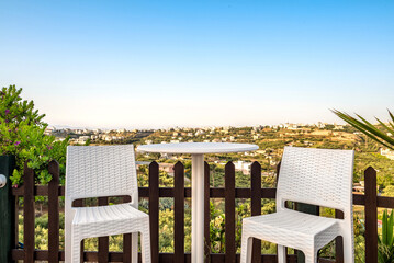 Poster - View to the terrace. There are  two white chairs and table, garden furniture. Panoramic view to the area. 