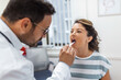 © Graphicroyalty - Doctor using inspection spatula to examine patient throat. ENT doctor doing throat exam of a woman. patient opened her mouth to throat check-up