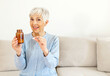 © Jelena Stanojkovic - Senior woman holding a bottle of medication, while smiling at the camera. Smiling mature women taking vitamins.