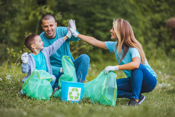Mother and father teach their son to recycle plastic in recycling containers. They volunteer in a public park, clean up trash.
