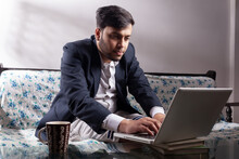 Indian Businessman Using Laptop At Home Wearing Suit
