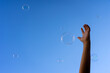 © JoseLuis - Hand of a child trying to catch some soap bubbles that rise to the sky