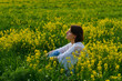© NADIN - a young girl in a boho cape is sitting in a field among yellow flowers and green grass