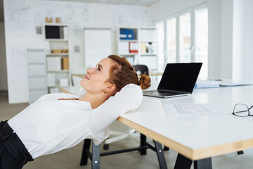 Wall Mural - Young business woman relaxing in office and looking up thoughtfully