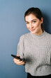 © contrastwerkstatt - Woman with cellphone in front of blue background with copy space