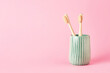 Two bamboo toothbrushes in a green ceramic holder. Eco-friendly, zero-waste concept. Selective focus