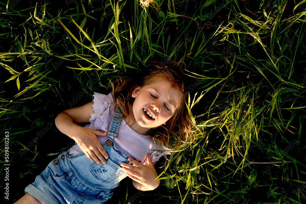 Caucasian little girl lying down on the grass Stock Photo | Adobe Stock