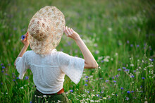 Rear, Back View Of Carefree Woman Wearing Straw Wicker Hat Walking In Summer Green Field. Copy, Empty Space For Text