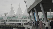 People Walking In Promenade Near Famous Canada Place Cruise Port And Conference Centre In Vancouver Bay, British Columbia, Canada