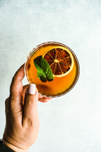 Overhead View Of A Woman Reaching For A Cocktail With A Slice Of Orange And Fresh Mint