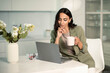 © Eva March - Business woman using laptop computer indoors at home office, with notes on papers, holding mug of coffee or tea, remote work and  freelancer, education and student, shopping online and application use