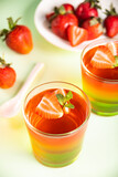 Fototapeta Kuchnia - Glasses of tasty summer dessert layered colorful jelly with fresh strawberries