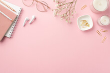 Business Concept. Top View Photo Of Workspace Candles Notepads Clips Pencils Stylish Glasses Earbuds And White Gypsophila Flowers On Isolated Pastel Pink Background With Copyspace