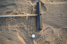 Golf Concept. Golf Ball And Rake Sand On Bunker In Beautiful Golf Course At Sunset Background