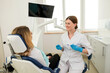 © Tania - A beautiful female dentist is talking to a patient while sitting in a chair.