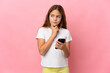 © luismolinero - Child over isolated pink background using mobile phone and thinking