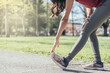 unrecognizable brunette young woman runner stretching calves muscles before running in park, copy space
