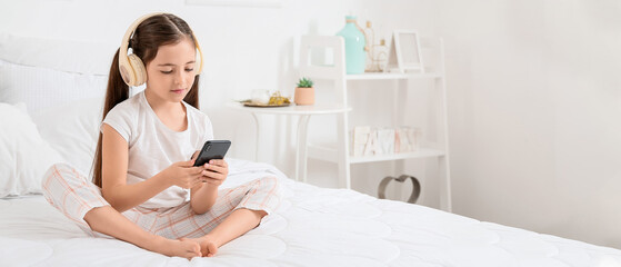 Sticker - Little girl with headphones and smartphone listening to music in bedroom