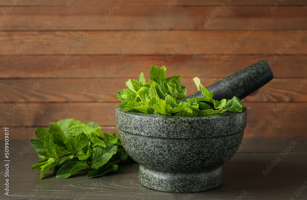 Mortar and pestle with mint leaves on wooden background