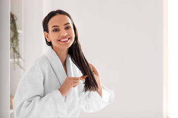 Young woman brushing her hair in bathroom