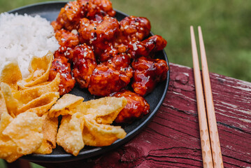 Wall Mural - General Tsos Chicken with white rice and crab rangoon on a dark dish