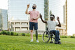 © Vane Nunes - Multiracial friends with disability using augmented reality futuristic glasses outdoor at park city - Focus on African man sitting on wheelchair