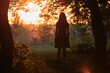 © bilanol - Back view of young woman in summer dress walking alone through evening dark forest